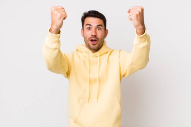 young handsome hicpanic man celebrating an unbelievable success like a winner, looking excited and happy saying take that!