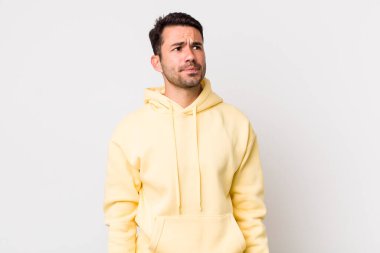 young handsome hicpanic man looking puzzled and confused, wondering or trying to solve a problem or thinking