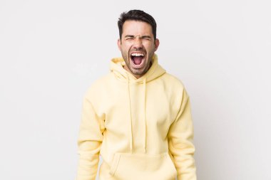 young handsome hicpanic man shouting aggressively, looking very angry, frustrated, outraged or annoyed, screaming no