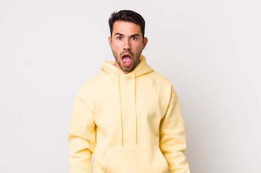 young handsome hicpanic man looking shocked, angry, annoyed or disappointed, open mouthed and furious
