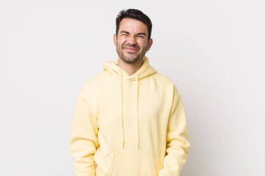 young handsome hicpanic man looking happy and friendly, smiling and winking an eye at you with a positive attitude