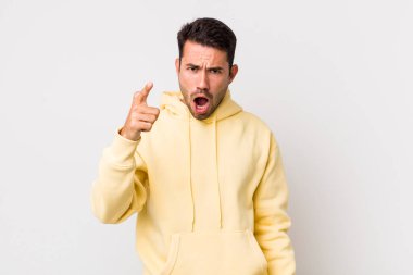 young handsome hicpanic man pointing at camera with an angry aggressive expression looking like a furious, crazy boss