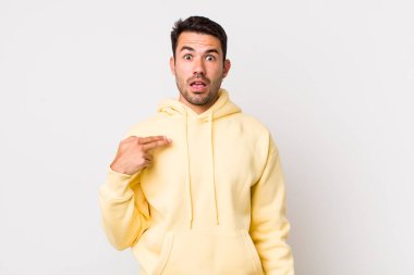 young handsome hicpanic man looking shocked and surprised with mouth wide open, pointing to self