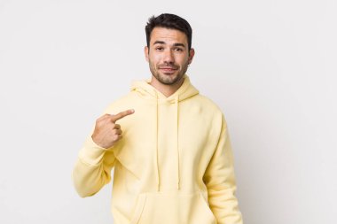 young handsome hicpanic man looking proud, confident and happy, smiling and pointing to self or making number one sign