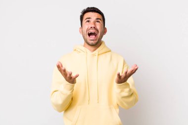 young handsome hicpanic man looking desperate and frustrated, stressed, unhappy and annoyed, shouting and screaming