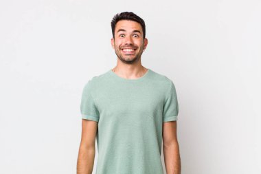 young handsome hicpanic man looking happy and pleasantly surprised, excited with a fascinated and shocked expression