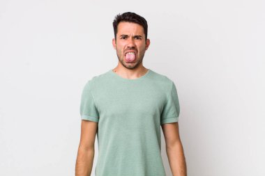 young handsome hicpanic man feeling disgusted and irritated, sticking tongue out, disliking something nasty and yucky