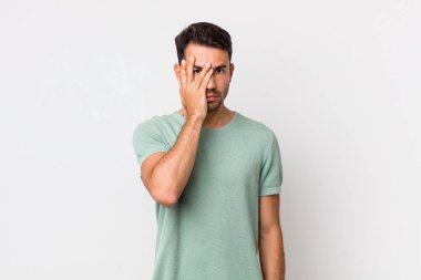 young handsome hicpanic man feeling bored, frustrated and sleepy after a tiresome, dull and tedious task, holding face with hand