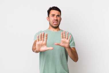 young handsome hicpanic man feeling terrified, backing off and screaming in horror and panic, reacting to a nightmare