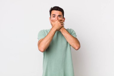 young handsome hicpanic man covering mouth with hands with a shocked, surprised expression, keeping a secret or saying oops