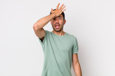 young handsome hicpanic man raising palm to forehead thinking oops, after making a stupid mistake or remembering, feeling dumb