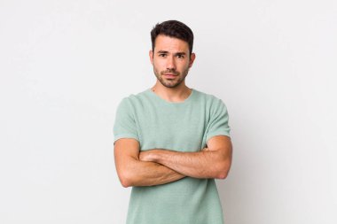 young handsome hicpanic man feeling displeased and disappointed, looking serious, annoyed and angry with crossed arms