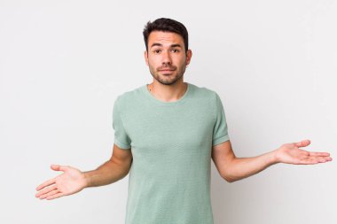 young handsome hicpanic man feeling puzzled and confused, unsure about the correct answer or decision, trying to make a choice