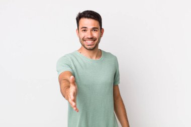 young handsome hicpanic man smiling, looking happy, confident and friendly, offering a handshake to close a deal, cooperating