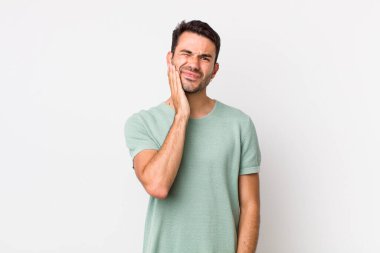 young handsome hicpanic man holding cheek and suffering painful toothache, feeling ill, miserable and unhappy, looking for a dentist