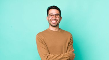 young handsome hicpanic man laughing shyly and cheerfully, with a friendly and positive but insecure attitude