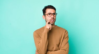 young handsome hicpanic man with surprised, nervous, worried or frightened look, looking to the side towards copy space