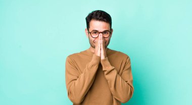 young handsome hicpanic man looking happy, cheerful, lucky and surprised covering mouth with both hands