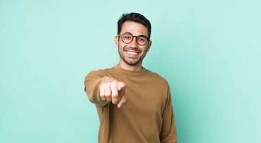 young handsome hicpanic man pointing at camera with a satisfied, confident, friendly smile, choosing you