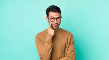 young handsome hicpanic man keeping an eye on you, not trusting, watching and staying alert and vigilant
