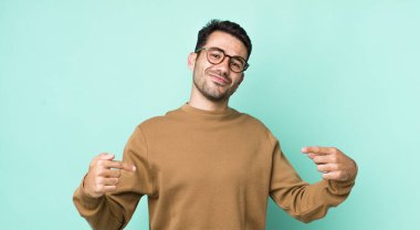 young handsome hicpanic man looking proud, arrogant, happy, surprised and satisfied, pointing to self, feeling like a winner