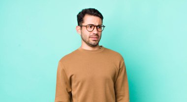 young handsome hicpanic man looking worried, stressed, anxious and scared, panicking and clenching teeth