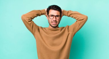 young handsome hicpanic man feeling stressed, worried, anxious or scared, with hands on head, panicking at mistake