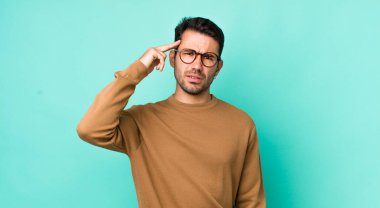 young handsome hicpanic man feeling confused and puzzled, showing you are insane, crazy or out of your mind