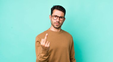 young handsome hicpanic man feeling angry, annoyed, rebellious and aggressive, flipping the middle finger, fighting back