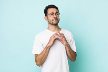 young handsome hicpanic man feeling proud, mischievous and arrogant while scheming an evil plan or thinking of a trick