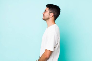 young handsome hicpanic man on profile view looking to copy space ahead, thinking, imagining or daydreaming