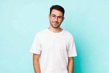 young handsome hicpanic man looking proud, confident, cool, cheeky and arrogant, smiling, feeling successful