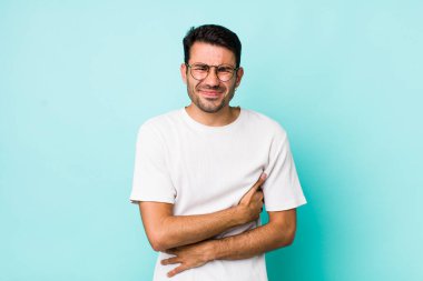 young handsome hicpanic man feeling anxious, ill, sick and unhappy, suffering a painful stomach ache or flu