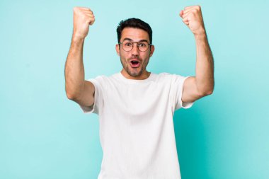 young handsome hicpanic man celebrating an unbelievable success like a winner, looking excited and happy saying take that!