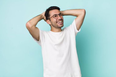 young handsome hicpanic man smiling and feeling relaxed, satisfied and carefree, laughing positively and chilling