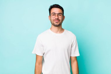 young handsome hicpanic man smiling positively and confidently, looking satisfied, friendly and happy