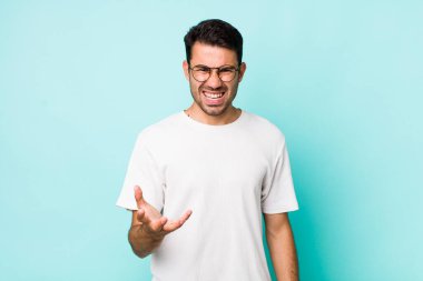 young handsome hicpanic man looking angry, annoyed and frustrated screaming wtf or whats wrong with you 