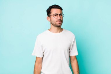 young handsome hicpanic man looking puzzled and confused, wondering or trying to solve a problem or thinking