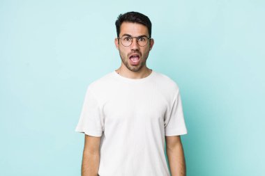 young handsome hicpanic man looking shocked, angry, annoyed or disappointed, open mouthed and furious