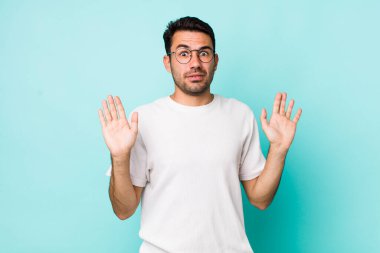 young handsome hicpanic man looking nervous, anxious and concerned, saying not my fault or I didnt do it 