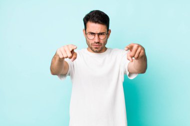 young handsome hicpanic man pointing forward at camera with both fingers and angry expression, telling you to do your duty