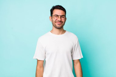 young handsome hicpanic man looking happy and friendly, smiling and winking an eye at you with a positive attitude