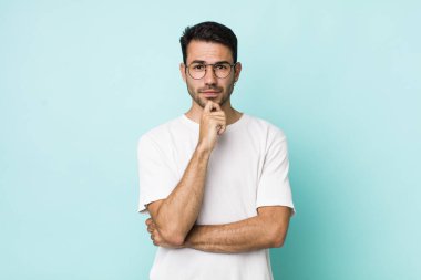 young handsome hicpanic man looking serious, confused, uncertain and thoughtful, doubting among options or choices
