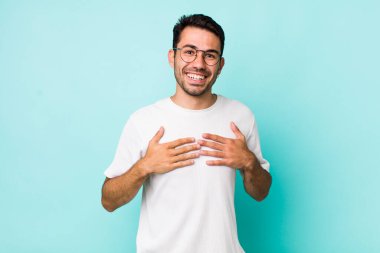 young handsome hicpanic man looking happy, surprised, proud and excited, pointing to self