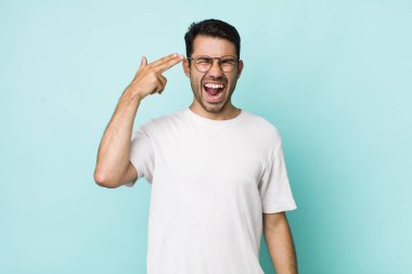 young handsome hicpanic man looking unhappy and stressed, suicide gesture making gun sign with hand, pointing to head