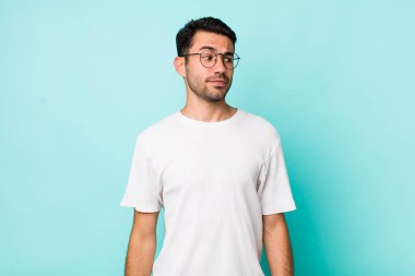 young handsome hicpanic man wondering, thinking happy thoughts and ideas, daydreaming, looking to copy space on side