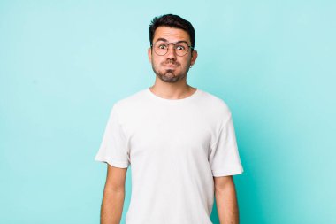 young handsome hicpanic man with a goofy, crazy, surprised expression, puffing cheeks, feeling stuffed, fat and full of food