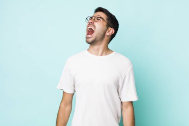 young handsome hicpanic man screaming furiously, shouting aggressively, looking stressed and angry