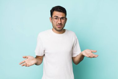 young handsome hicpanic man feeling clueless and confused, not sure which choice or option to pick, wondering
