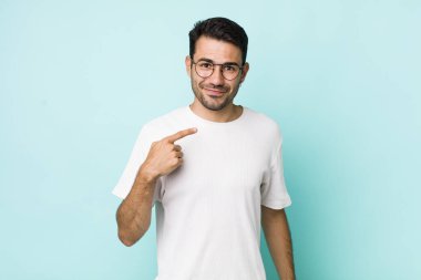 young handsome hicpanic man looking proud, confident and happy, smiling and pointing to self or making number one sign